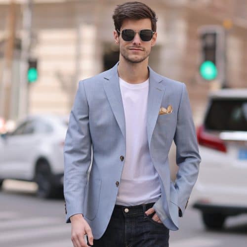 Crafted from a premium wool blend consisting of 70% wool and 30% advanced polyester, this slim-fit men's lightweight casual blazer features a two-button single-breasted closure, a standard 7–9 cm notch lapel, practical 3D patch pockets, double back vents, and a rounded hem. Designed with a western/urban style for the summer season, it offers a thin profile in a light gray-blue denim look color, available in sizes 42 through 52.